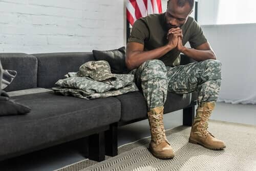Military man sitting on couch think about his domestic violence charges. 